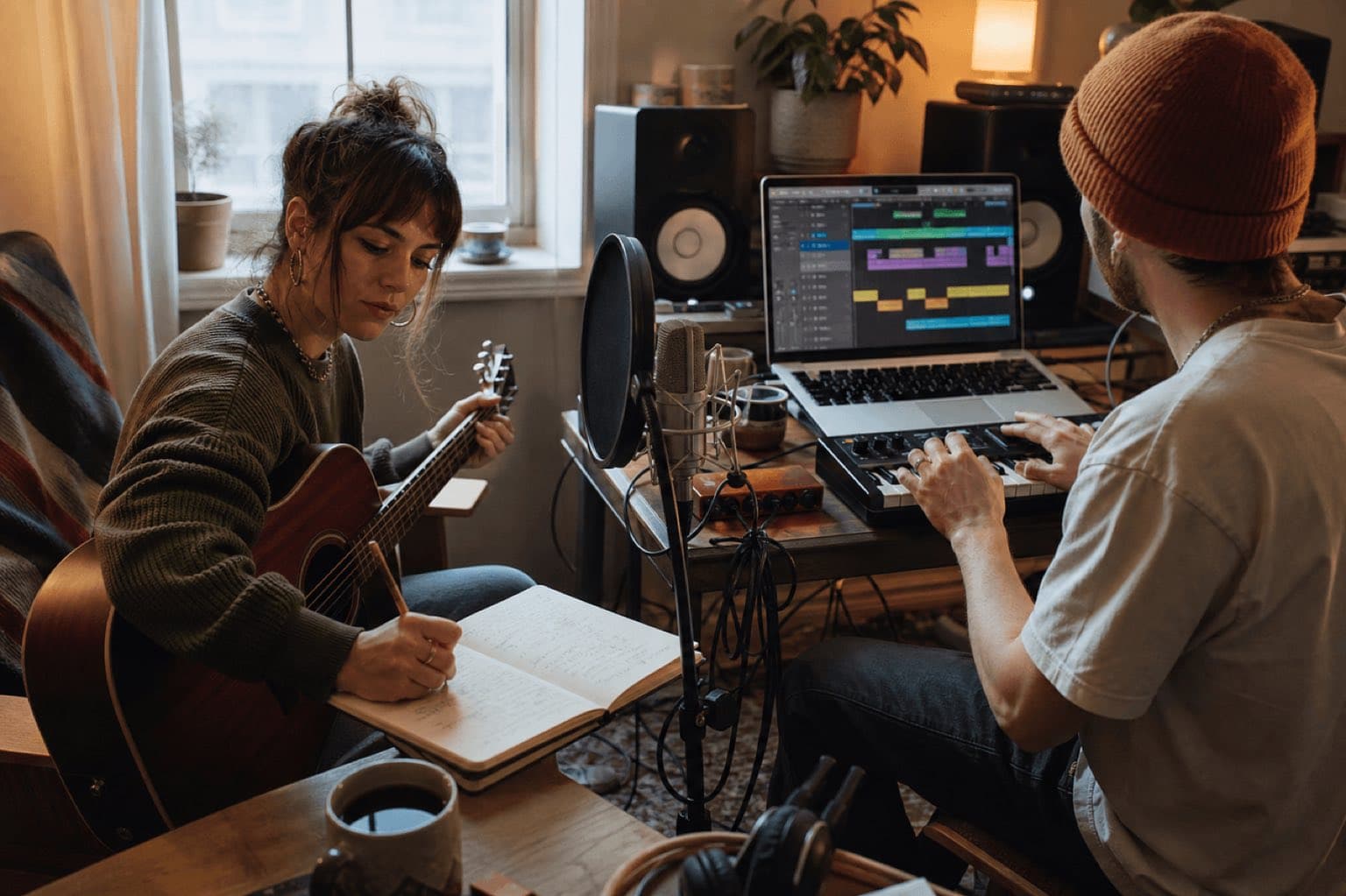 Dos músicos reales escribiendo, tocando guitarra y produciendo una canción en estudio doméstico