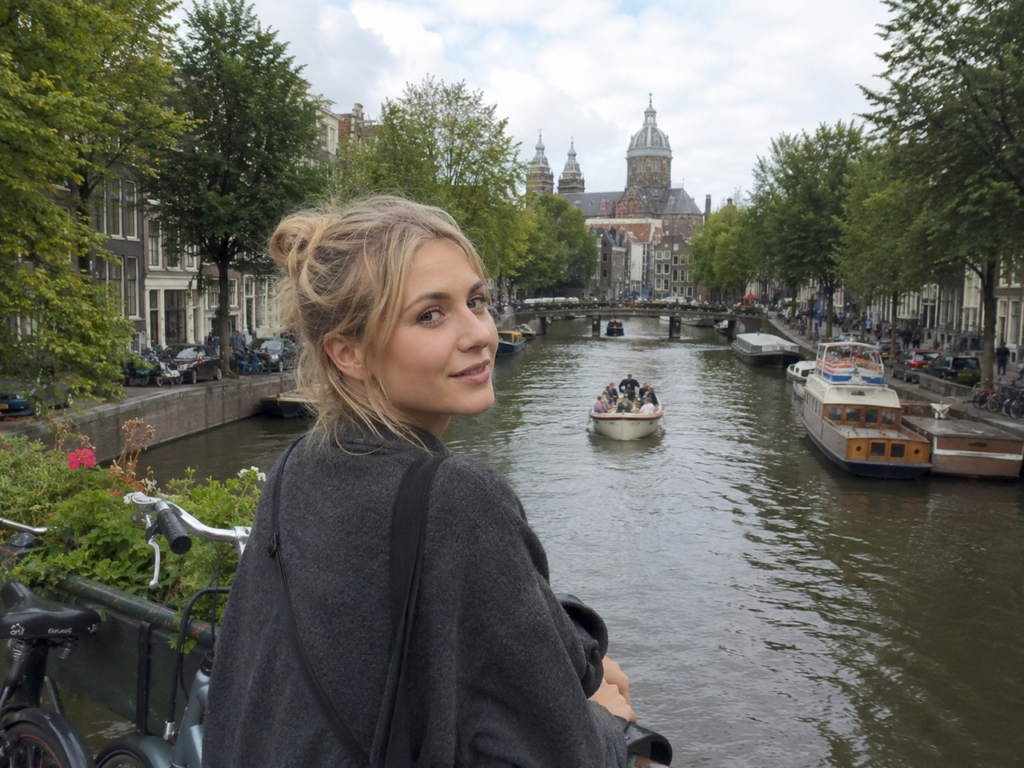 Woman standing by a canal in Amsterdam, showing typical travel vlog footage used when adding music to a video.
